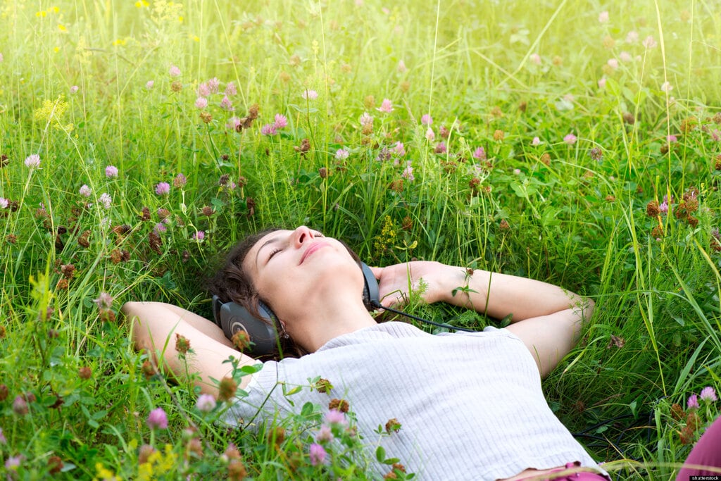 a girl listening to music laying on the grass